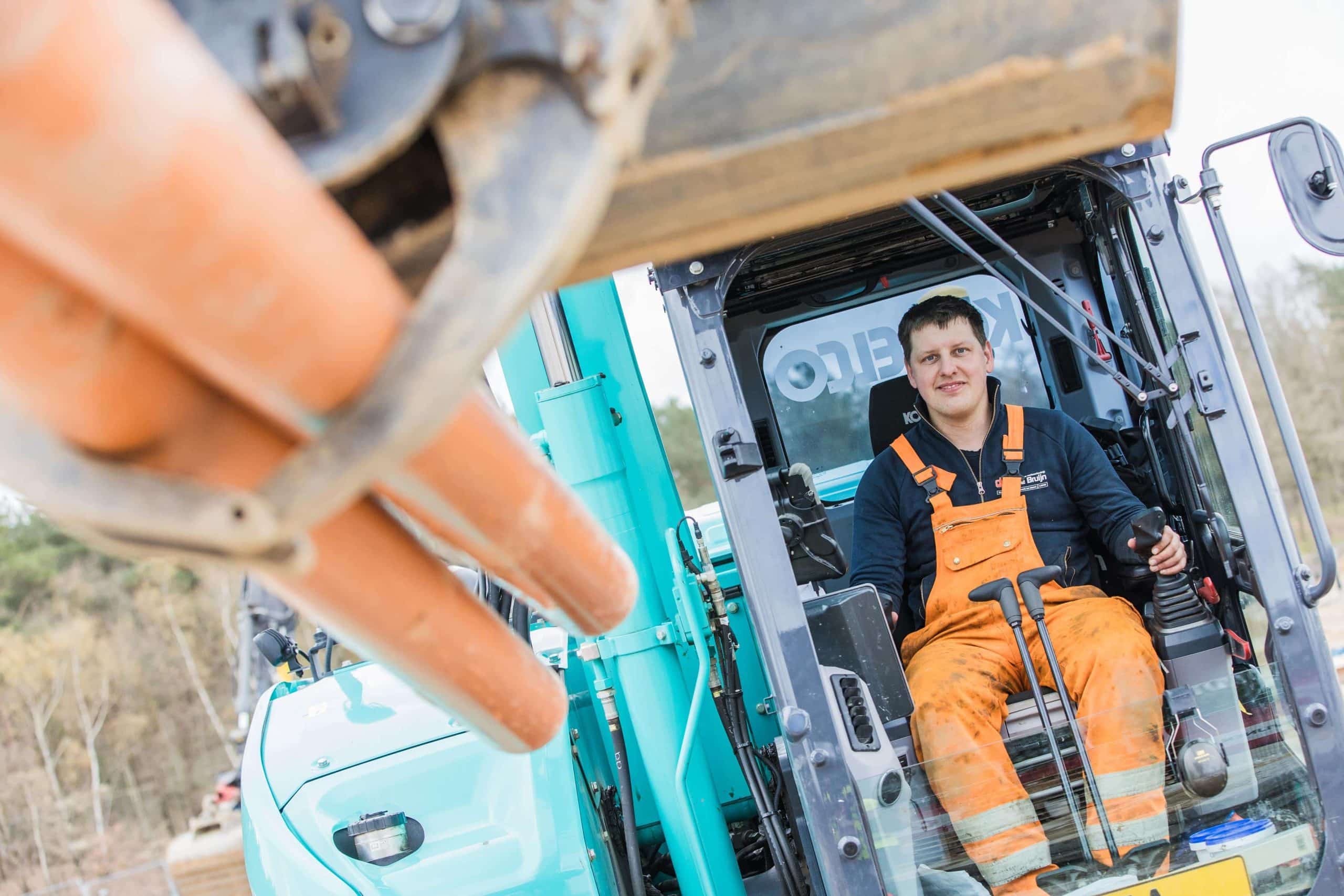 Medewerker in graafmachine tijdens grondwerkzaamheden